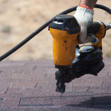 Contractor installing asphalt shingles on roof